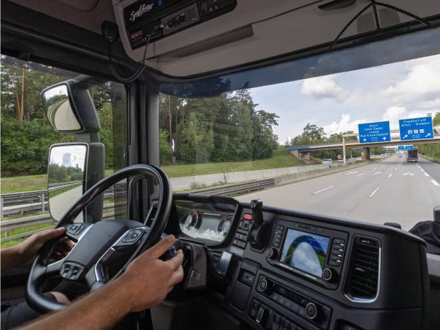 Blick ins LKW-Führerhaus mit Aussicht auf Straße symbolisch für Restlenkzeiten